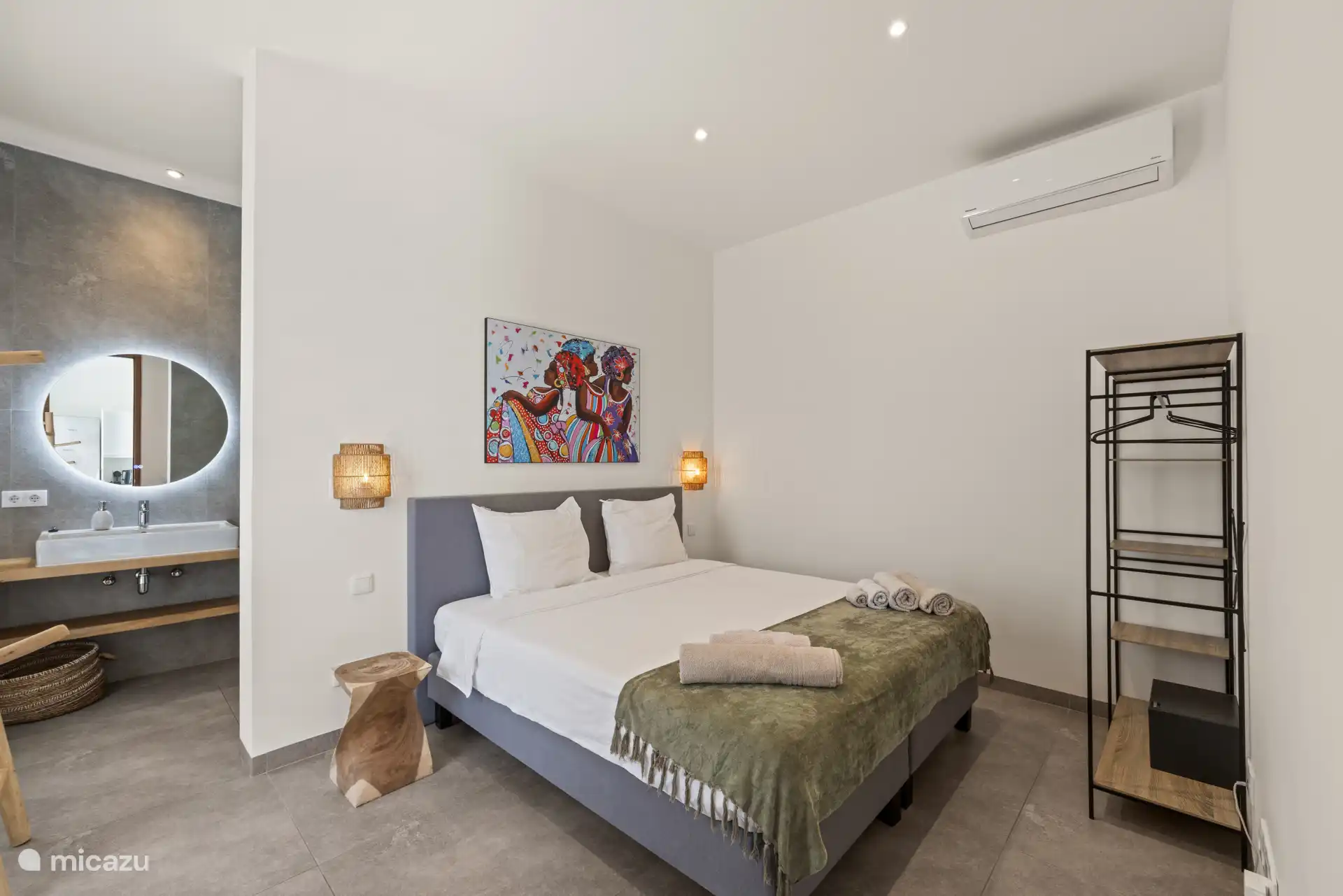 De slaapkamer is voorzien van een tweepersoonsbed, airconditioning en directe toegang tot een moderne ensuite badkamer met douche en toilet.