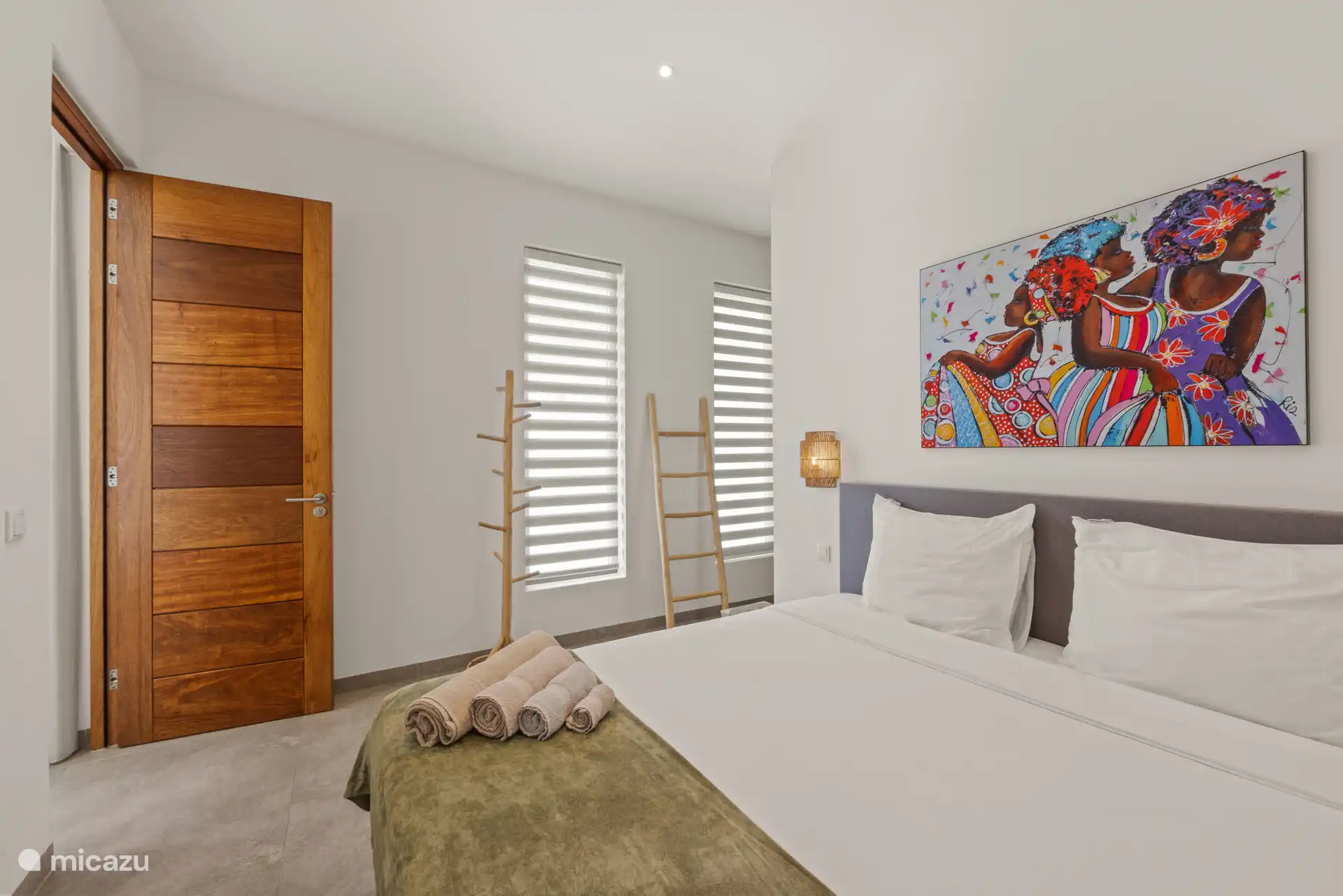 De slaapkamer is voorzien van een tweepersoonsbed, airconditioning en directe toegang tot een moderne ensuite badkamer met douche en toilet.