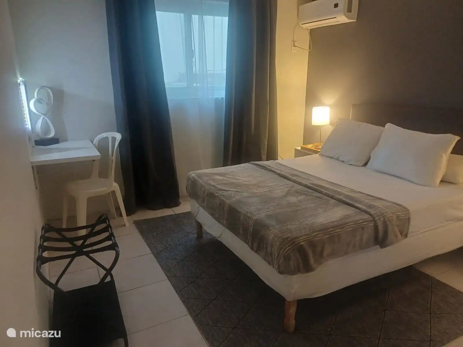 Dormitorio con cama matrimonial cómoda, ropa de cama limpia, iluminación ambiental y aire acondicionado. Un espacio tranquilo y con estilo donde puedes relajarte y disfrutar de tu sueño nocturno