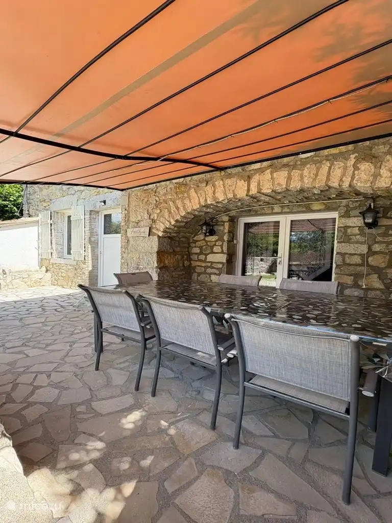 Groot, schaduwrijk privéterras met een grote eettafel, perfect voor je familiemaaltijden.