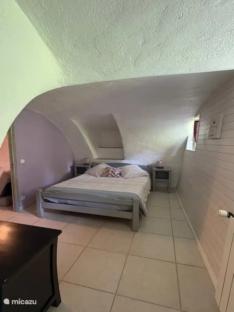 Hoofdslaapkamer onder een authentiek gewelf, die de uitstraling van steen combineert met modern comfort.