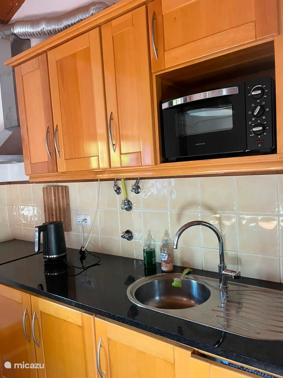 Praktische keuken met inductie 4 pits kookplaat, oven, waterkoker, koffieapparaat met Delta-cups en een koelkast met vriesvakje. Er is voldoende werk-en opbergruimte om zelf te koken