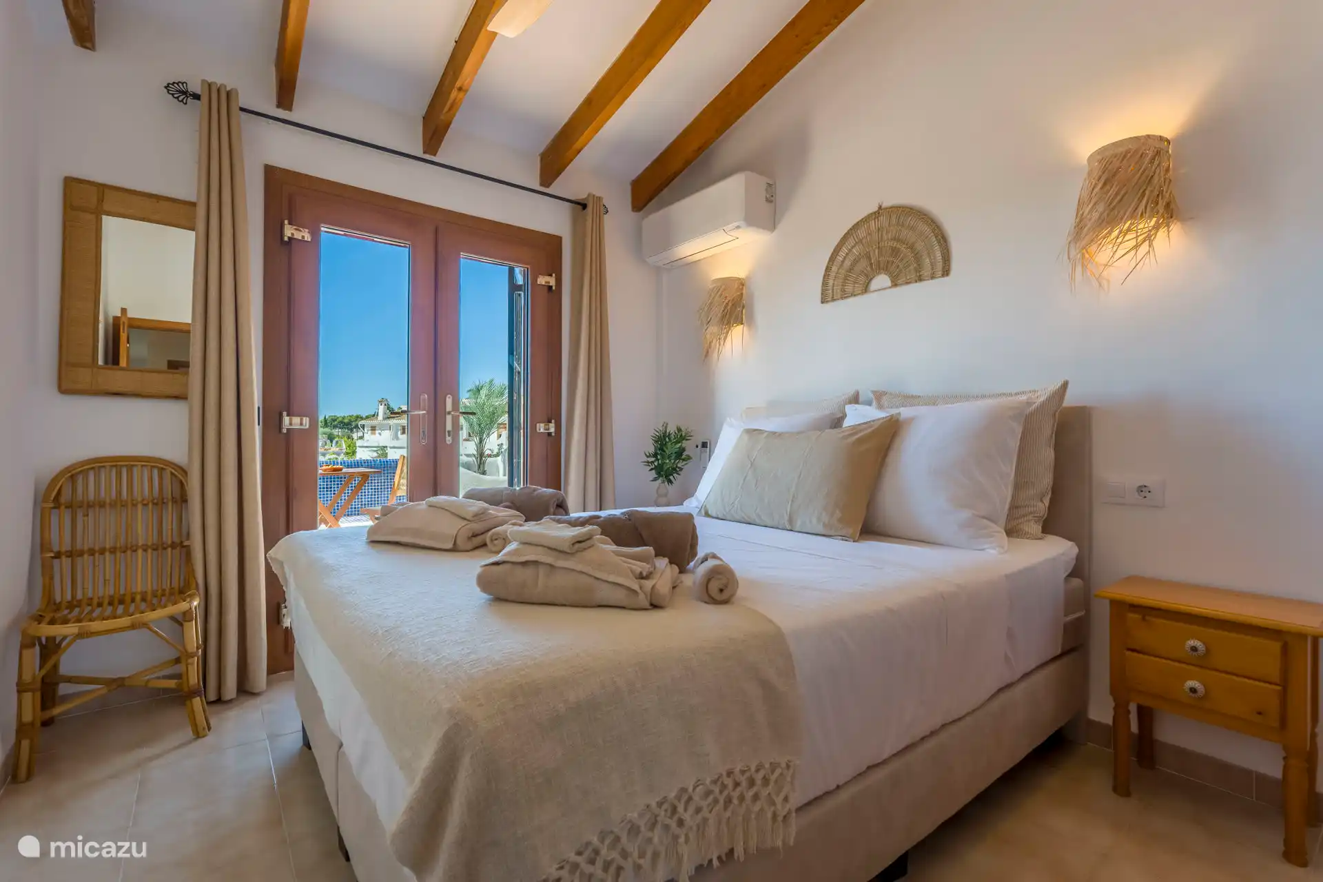 Das Hauptschlafzimmer mit Terrassentüren zum Balkon und Meerblick
