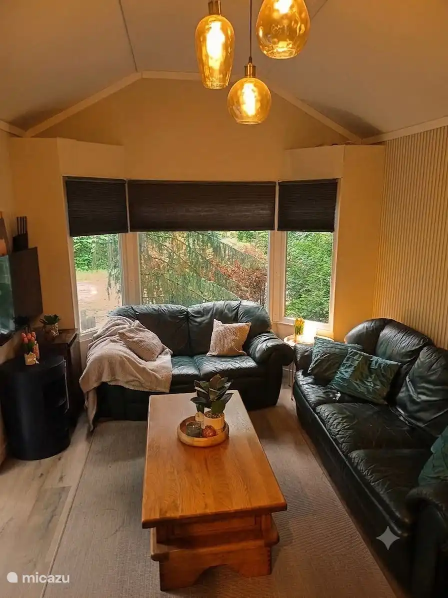 Gezellige en lichte woonkamer met comfortabele zitgelegenheid en uitzicht op het groen. Een heerlijke plek om te ontspannen, samen te komen en volop te genieten van uw verblijf.