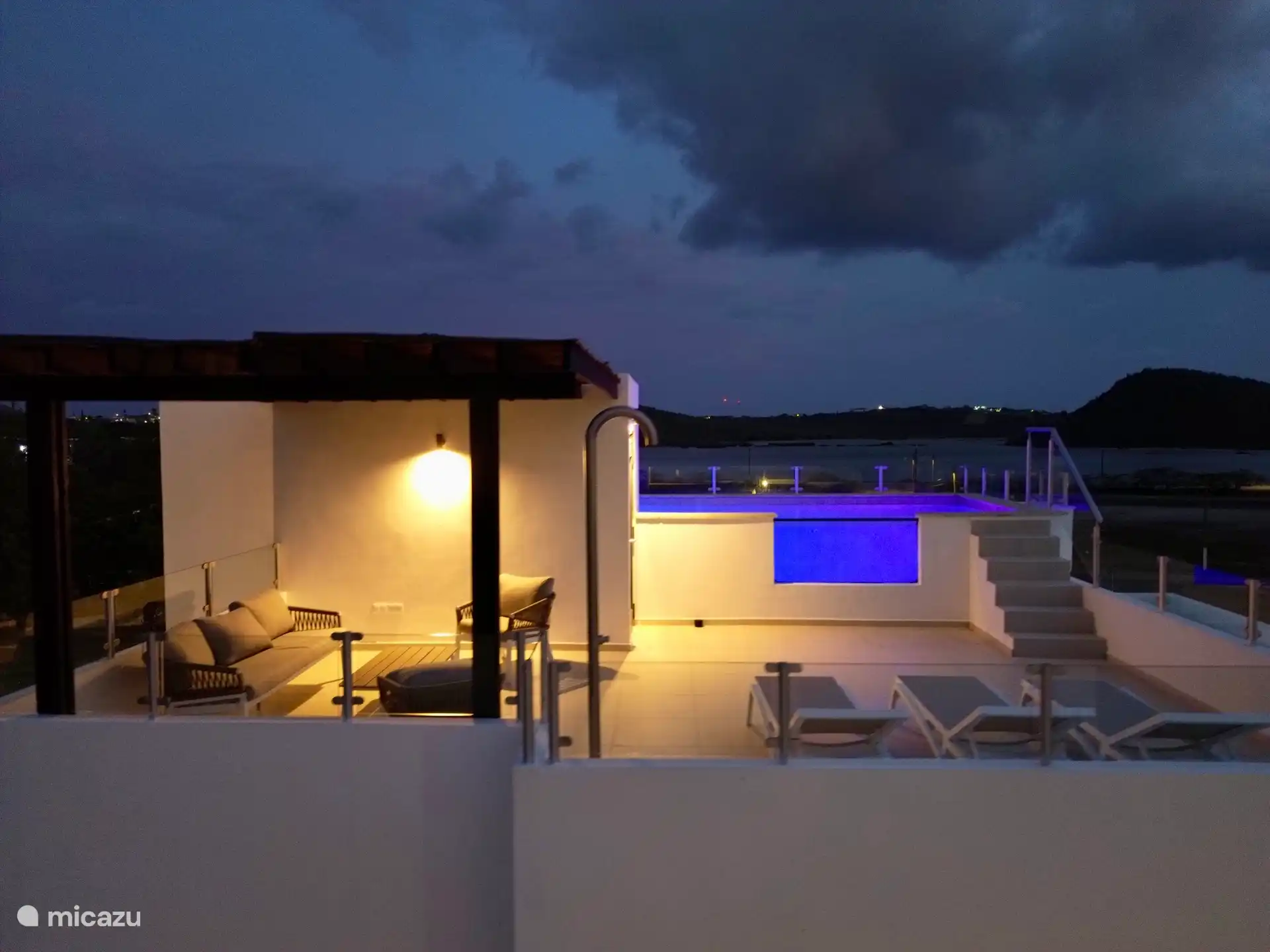 Roof terrace in evening light and pool lights on.