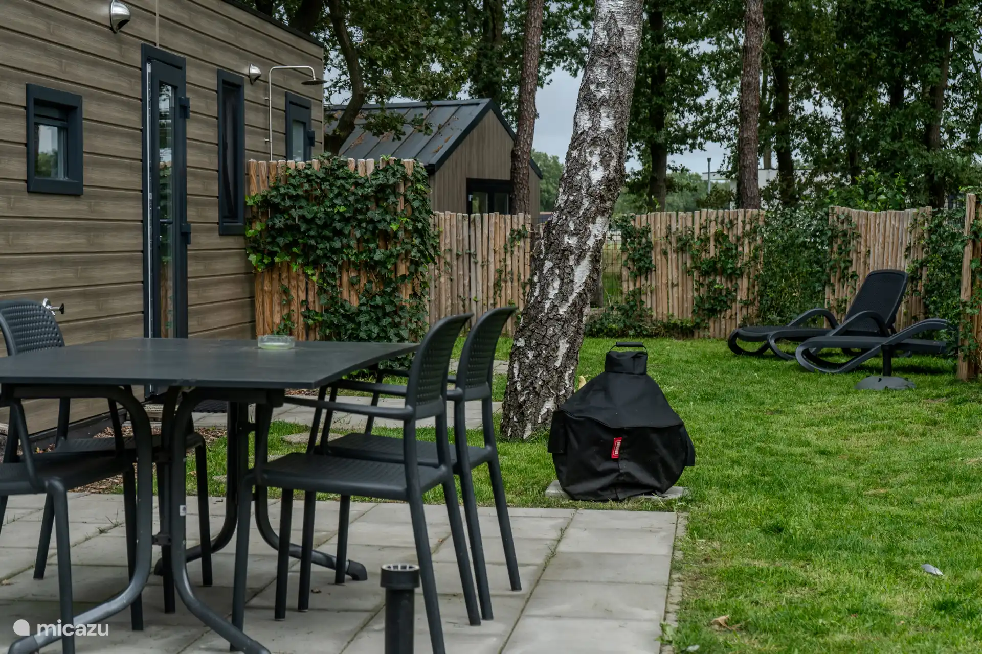 Onze tuin met BBQ en ligstoelen