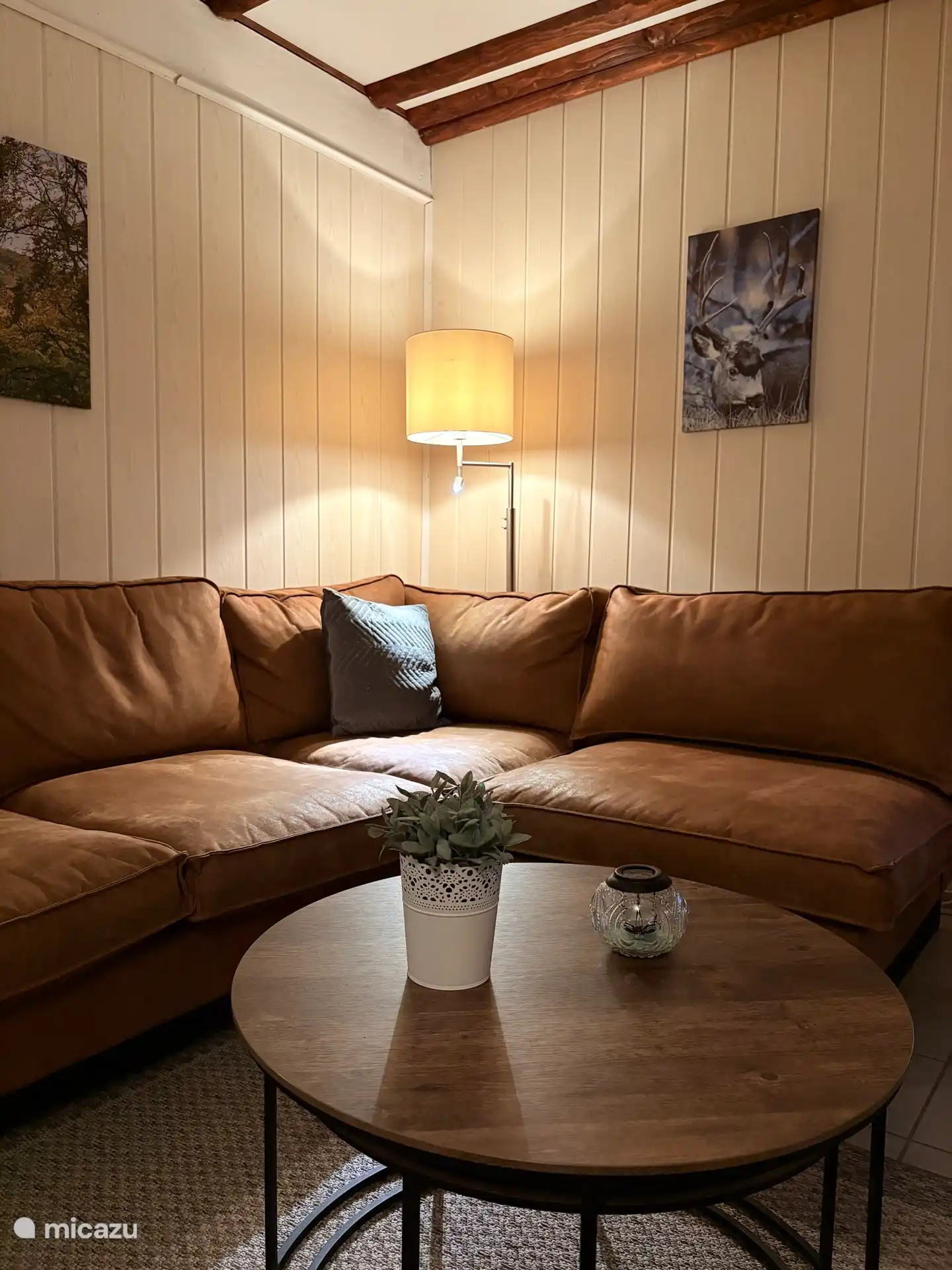 Moderne hoekbank en bijzettafels met sfeerverlichting in de avond.