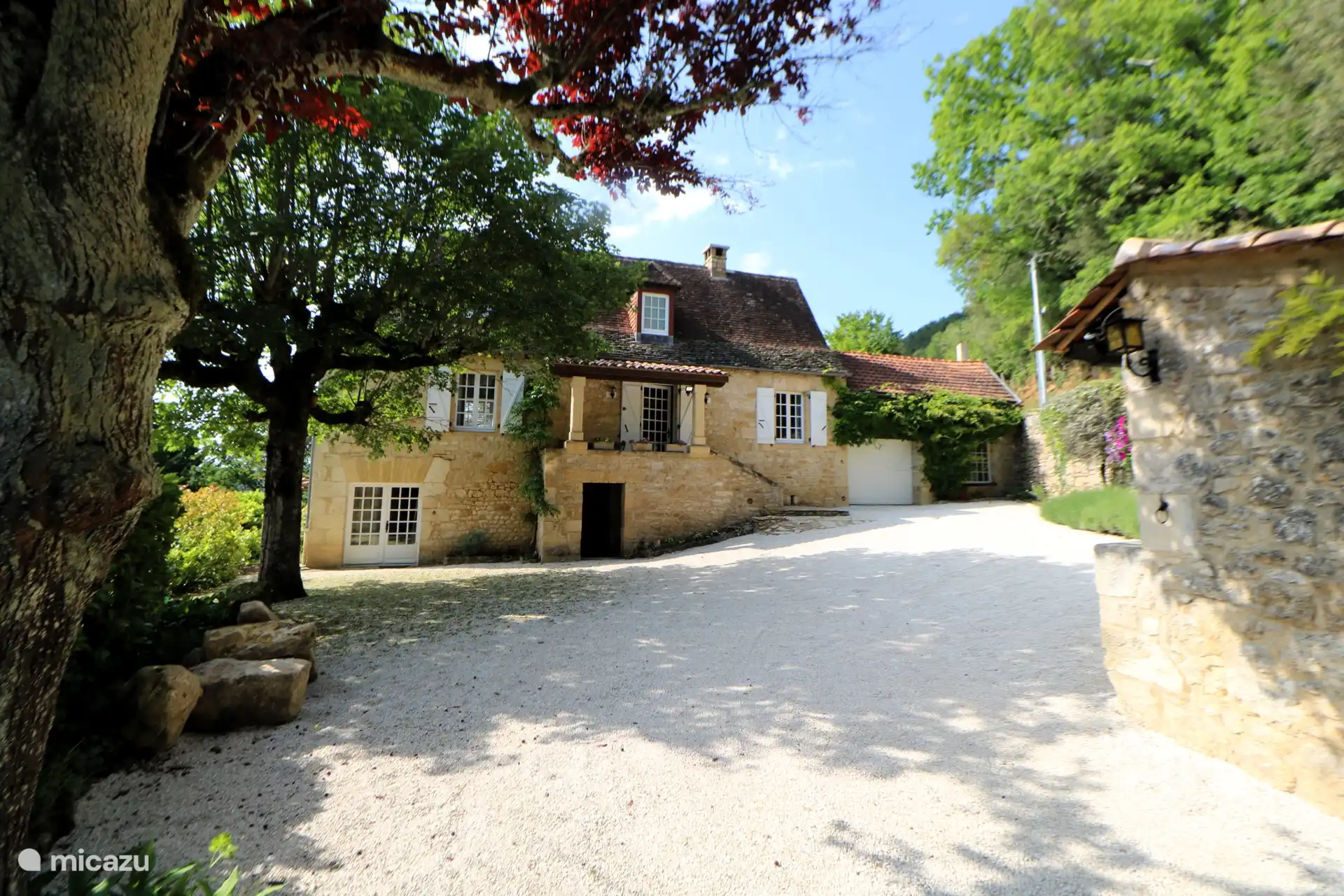 La entrada y la fachada de la casa, con la característica fachada de piedra del Périgord.