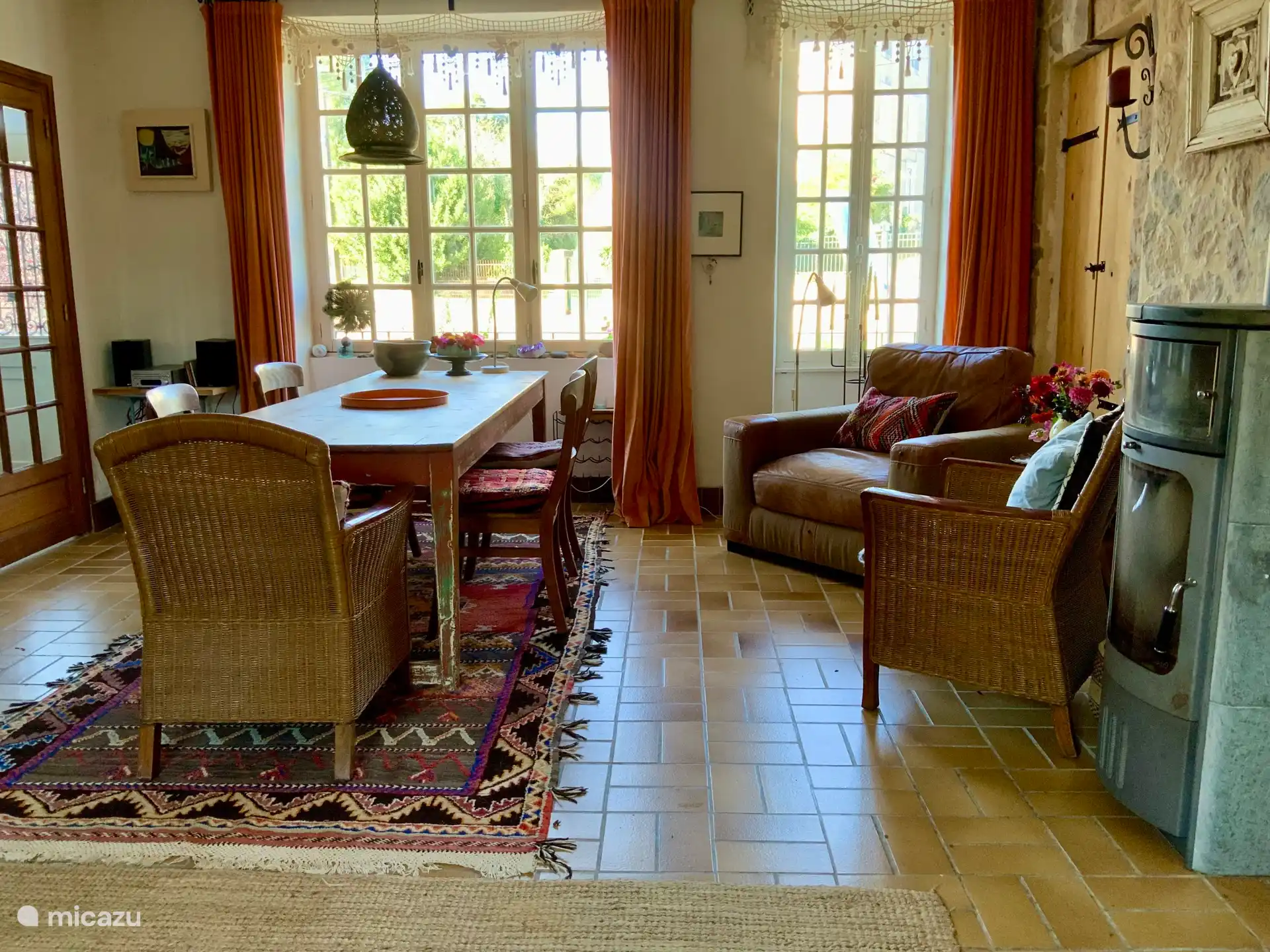 Grote woonkeuken met goede speksteen houtkachel, lange tafel, fauteuil, vaatwasser, wasmachine, fornuis met oven