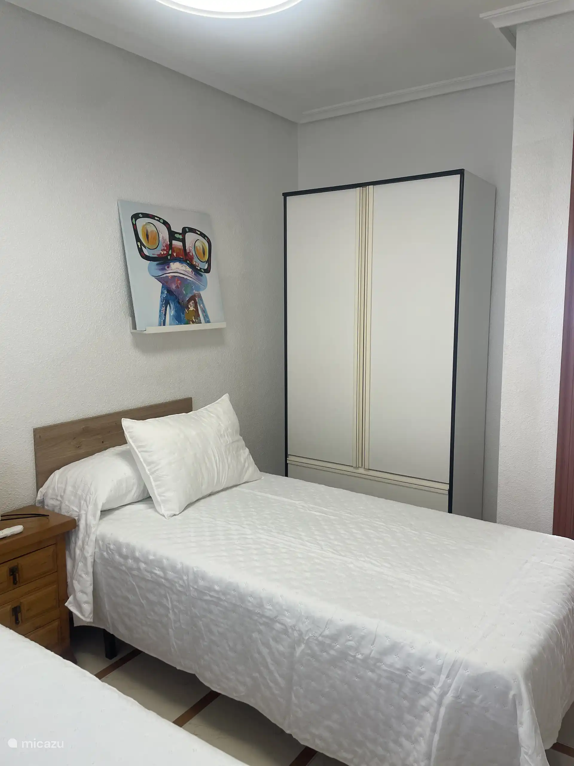 Vue sur la deuxième chambre avec un des lits et une armoire.