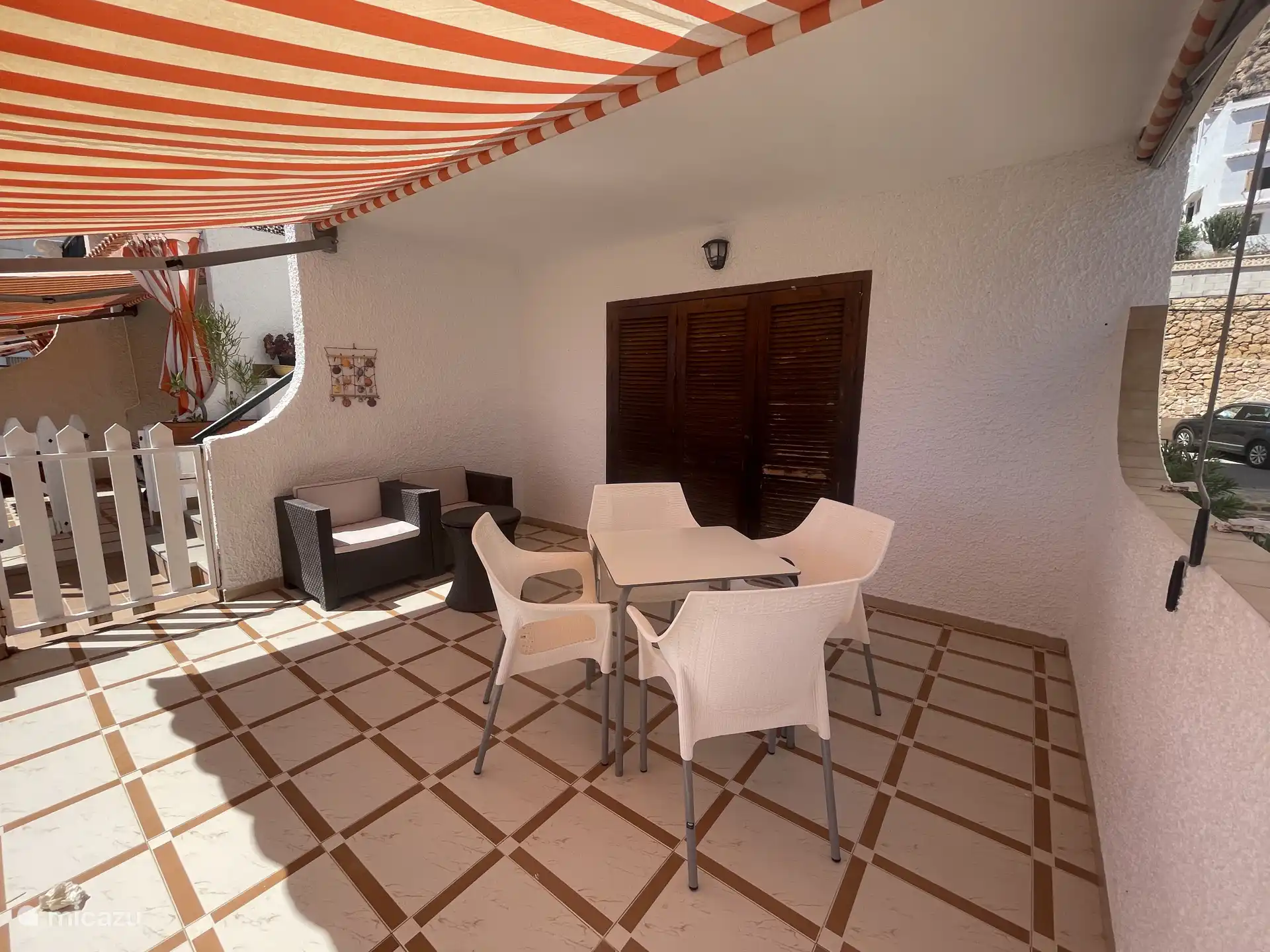 Terrasse avec table à manger extérieure, espace salon et auvent.