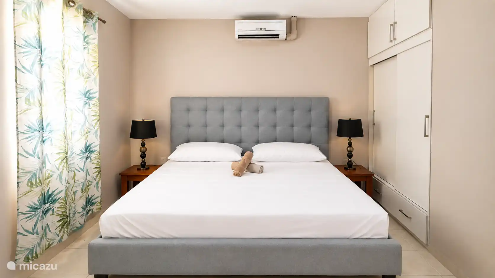 Comfortabele slaapkamer met een ruim bed, frisse lakens en airco. Rustige kleuren en zachte verlichting zorgen voor een ontspannen sfeer na een dag zon, zee en strand.