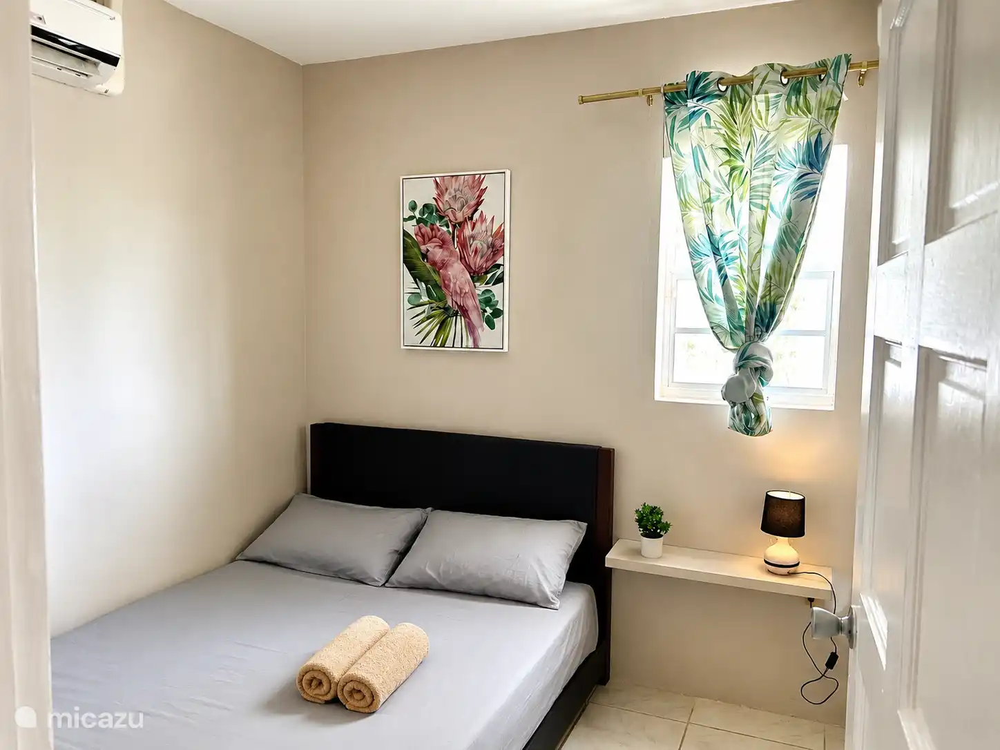 Comfortabele slaapkamer met een ruim bed, frisse lakens en airco. Rustige kleuren en zachte verlichting zorgen voor een ontspannen sfeer na een dag zon, zee en strand.