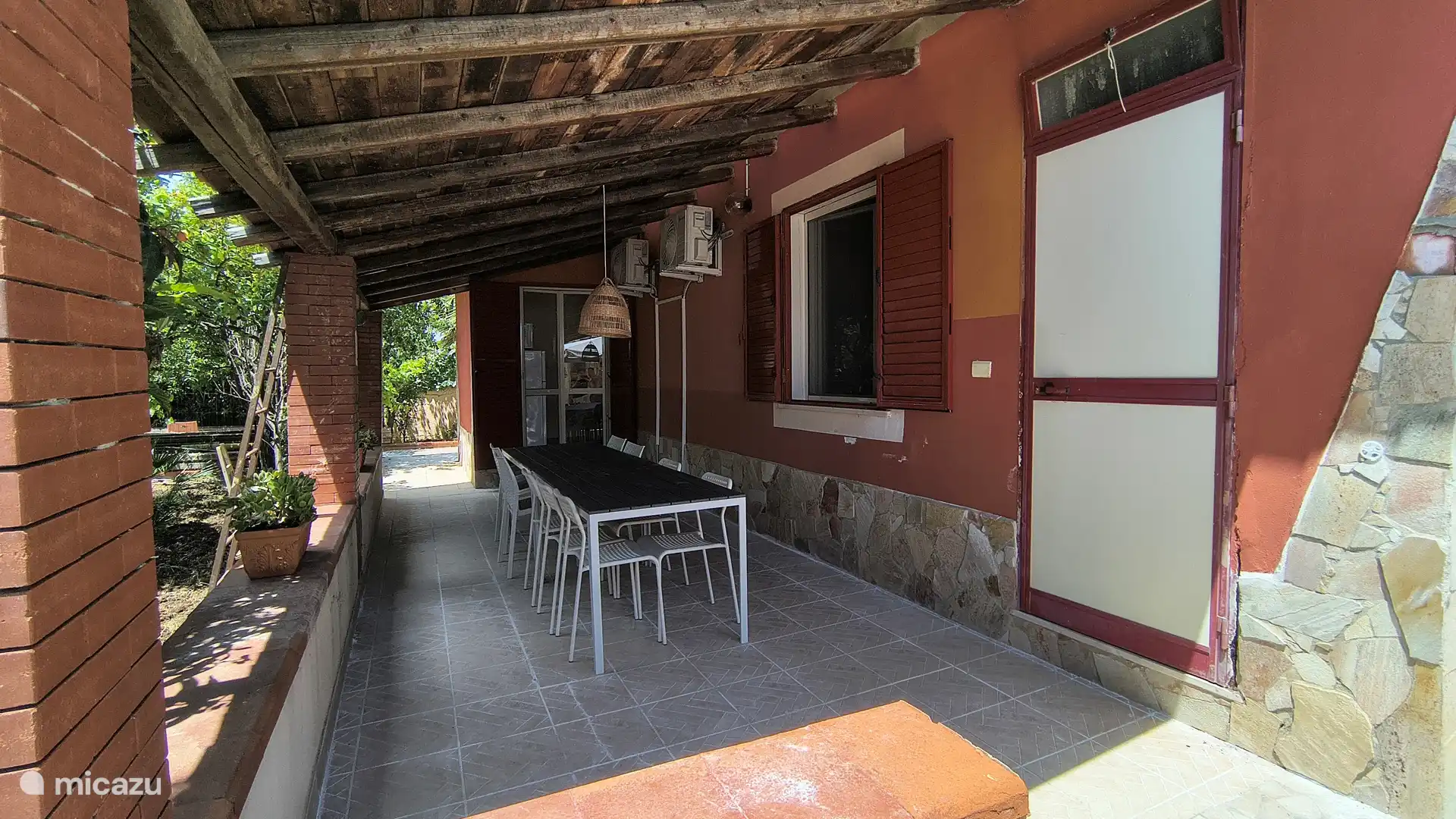 Grote eettafel met stoelen onder de veranda.