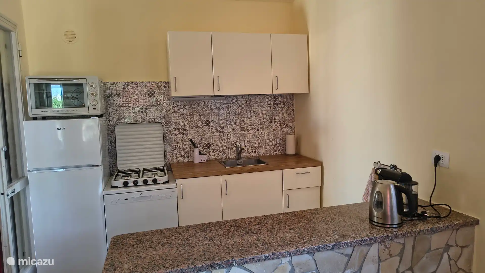 Open keuken met koelkast vaatwasser,kookplaat oventje,espressoapparaat en waterkoker.