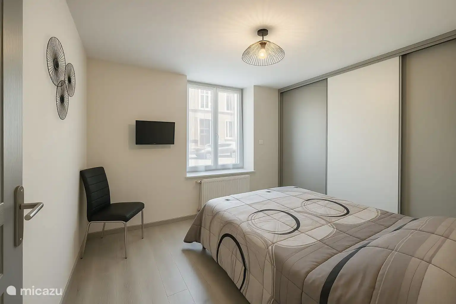 Slaapkamer met tweepersoonsbed: nog een uitzicht op de opslagruimte en de aan de muur gemonteerde tv.