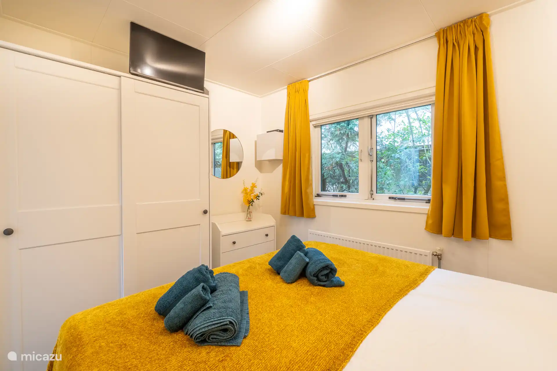 Comfortabele slaapkamer met tweepersoonsbed, ruime kledingkast en uitzicht op het groen.