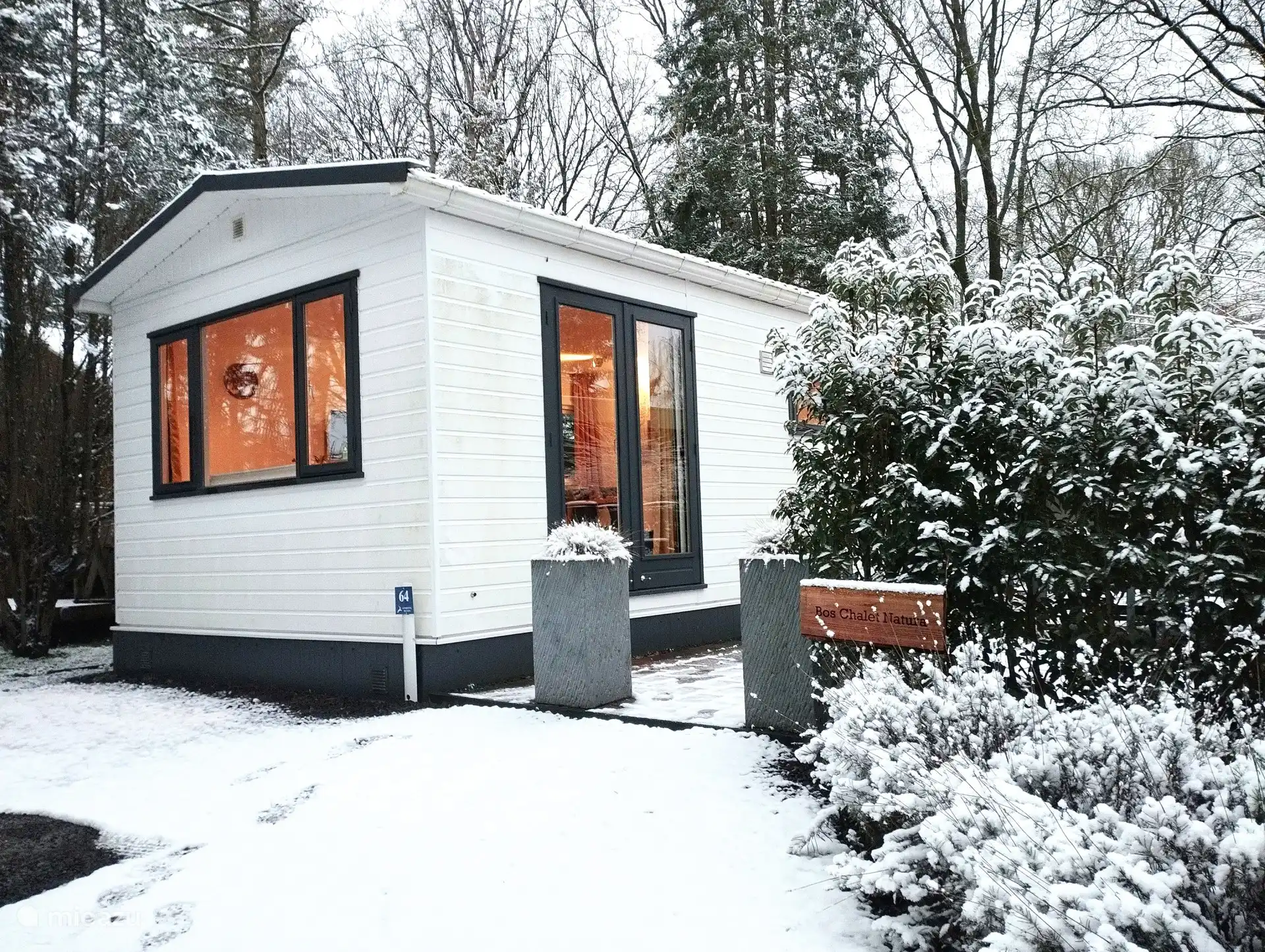 os Chalet Natura in winterse sferen, omringd door een prachtig wit landschap.