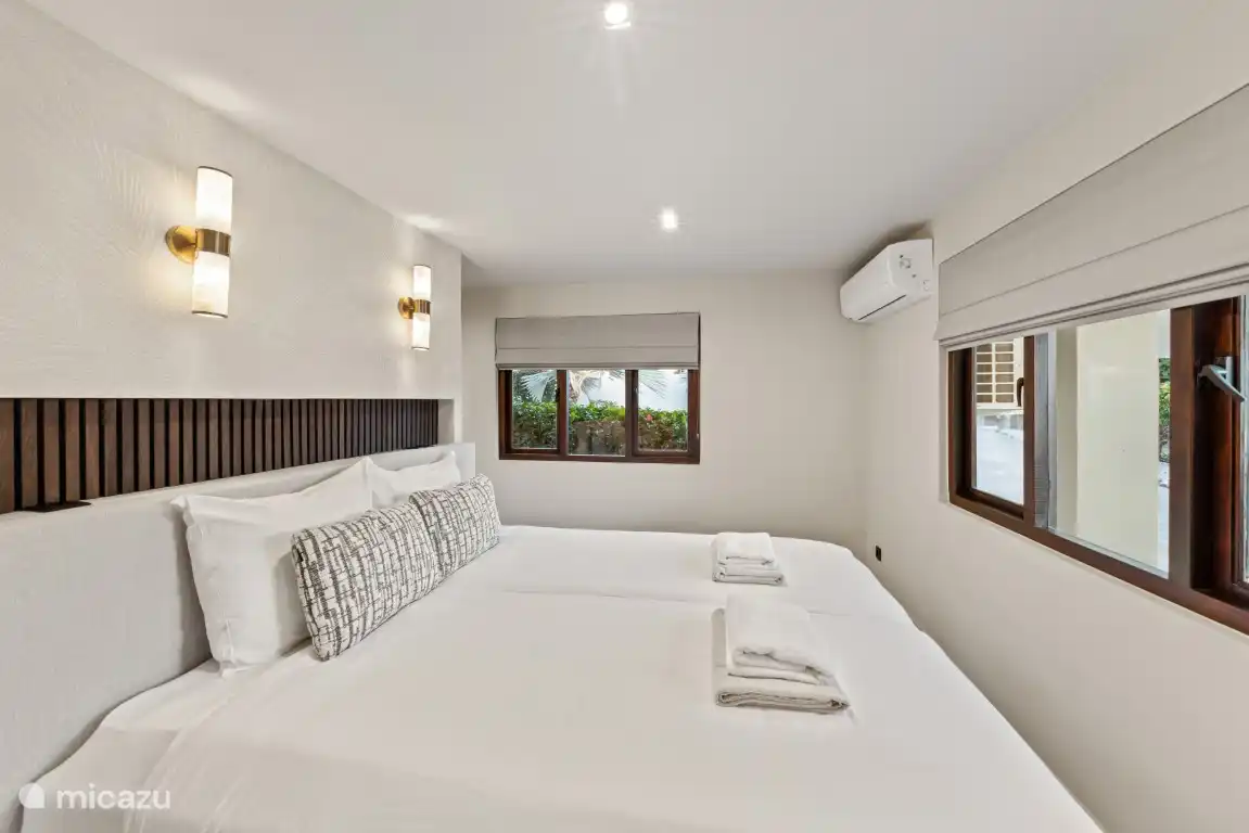 Dormitorio 2 con cama king size (1,80x2,20m) y aire acondicionado. Detrás de la cama hay un armario, una caja fuerte y un baño privado en suite. 