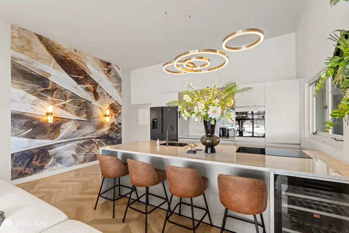 Isla de cocina con nevera/congelador americano y máquina de cubitos de hielo, cocina de inducción, nevera de vinos, horno/microondas, freidora de aire, lavavajillas y grifo Quooker.