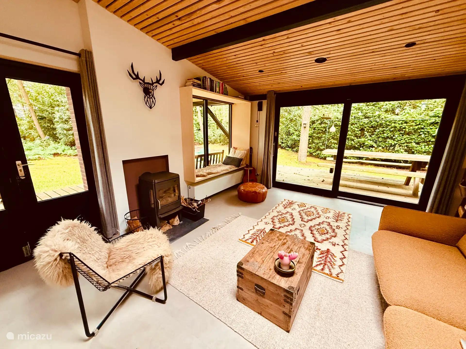Salón con estufa acogedora y una preciosa ventana de estar con vistas al jardín