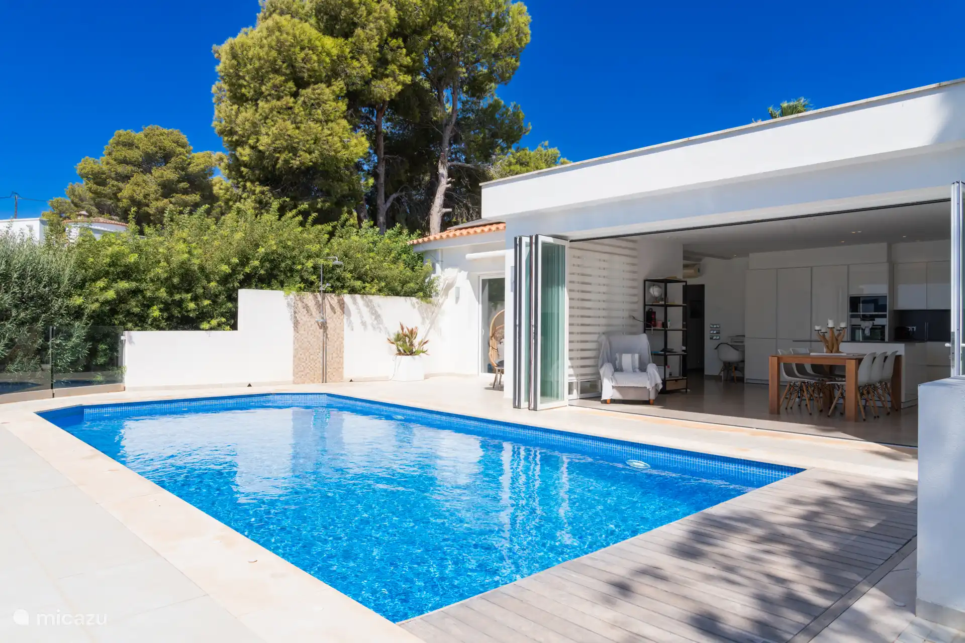 Schwimmbecken mit Terrasse und Schiebetüren zum Wohnzimmer hin