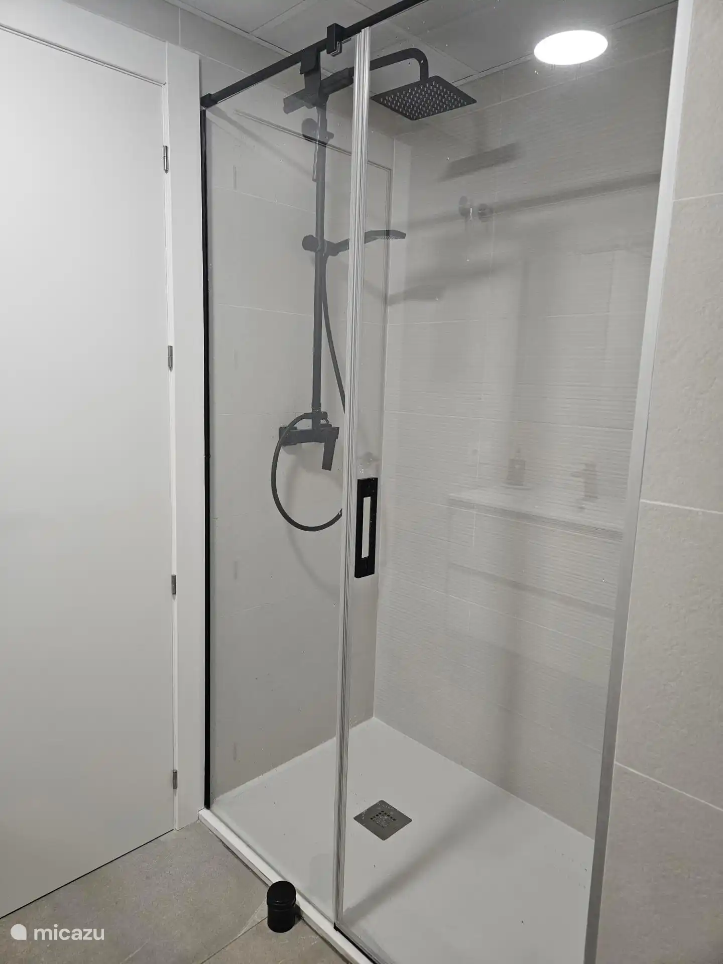 La salle de bain dispose d’une douche avec une porte vitrée et d’un jet d’eau fin et puissant.