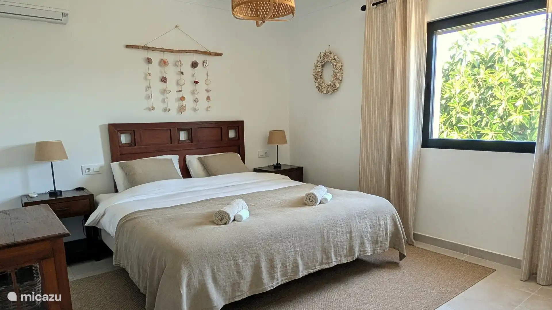 Lichte slaapkamer met tweepersoonsbed en uitzicht op het groen. Een fijne plek om na een zonnige dag heerlijk bij te komen.