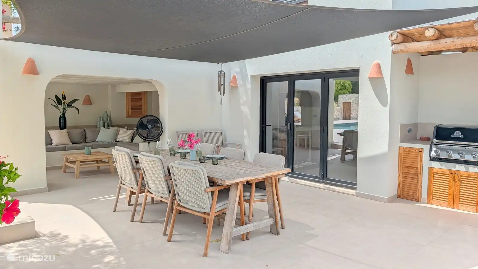 Overdekt terras met buitentafel en loungehoek. Hier eet je samen in de schaduw, met het zwembad op een paar stappen afstand.