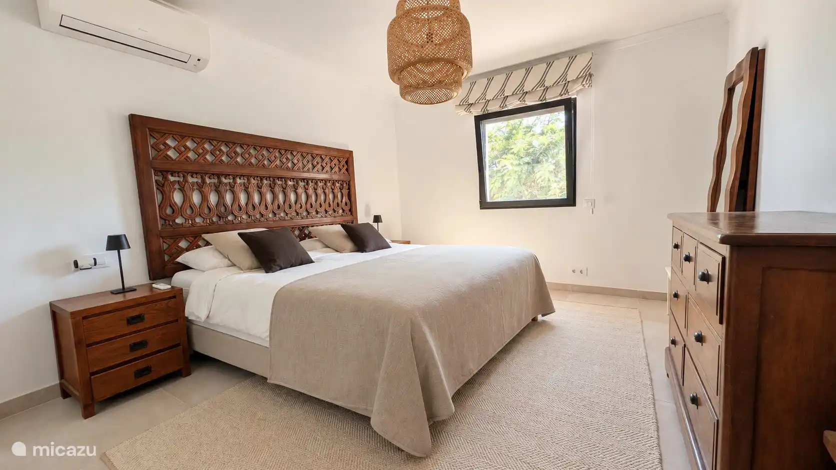 Slaapkamer met tweepersoonsbed en houten hoofdbord in Spaanse stijl. Rustige kleuren zorgen voor een goede nachtrust.