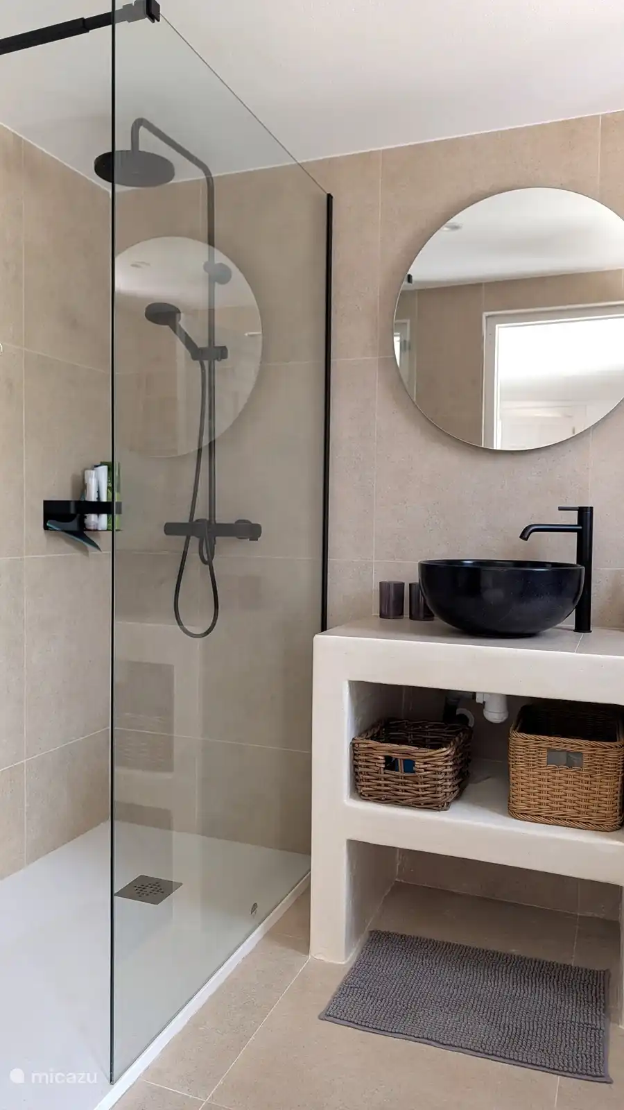 Moderne badkamer met inloopdouche en zwarte designkraan. Lekker opfrissen na een dag aan het zwembad of op het strand.