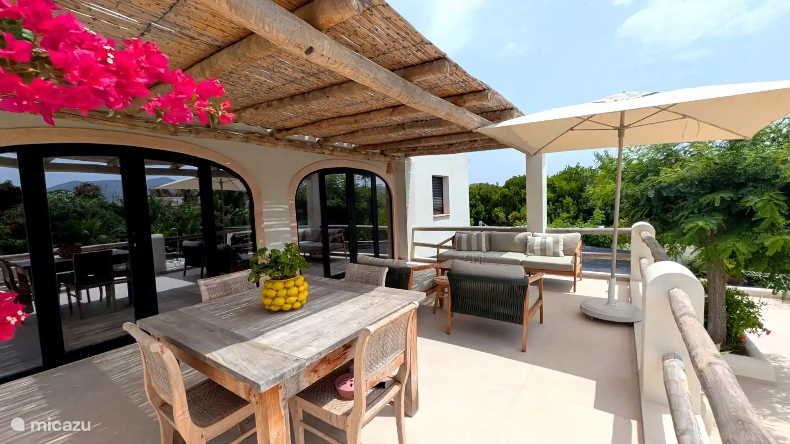 Overdekt terras met grote eettafel en loungeset. De perfecte plek voor lange lunches en een glas wijn als de avond valt.