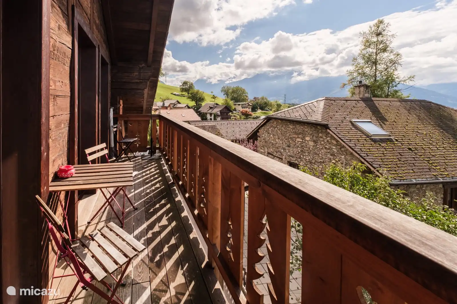 Het grote zonnige balkon met uitzicht op de daken en bergen