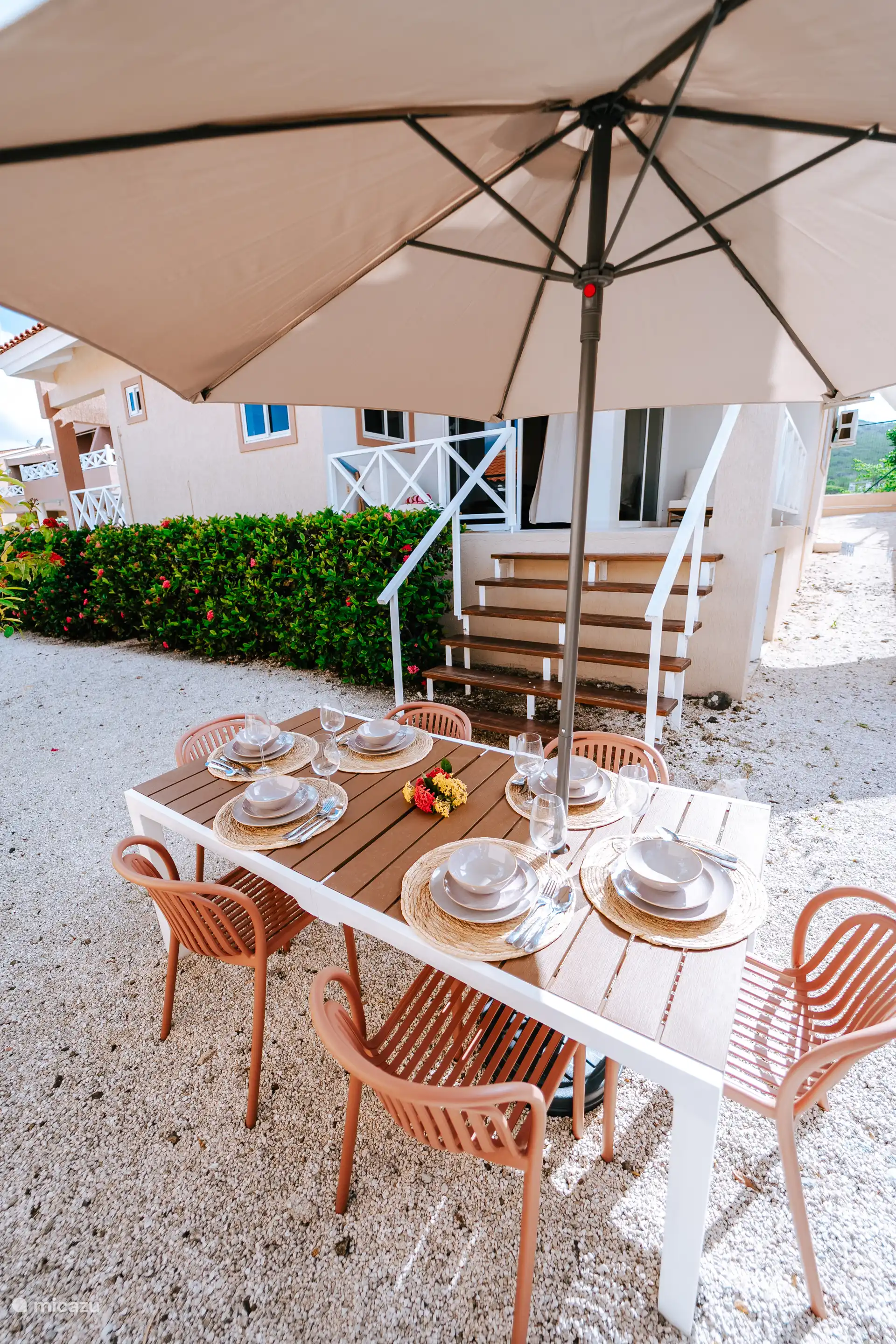 Eettafel met parasol naast de bungalow