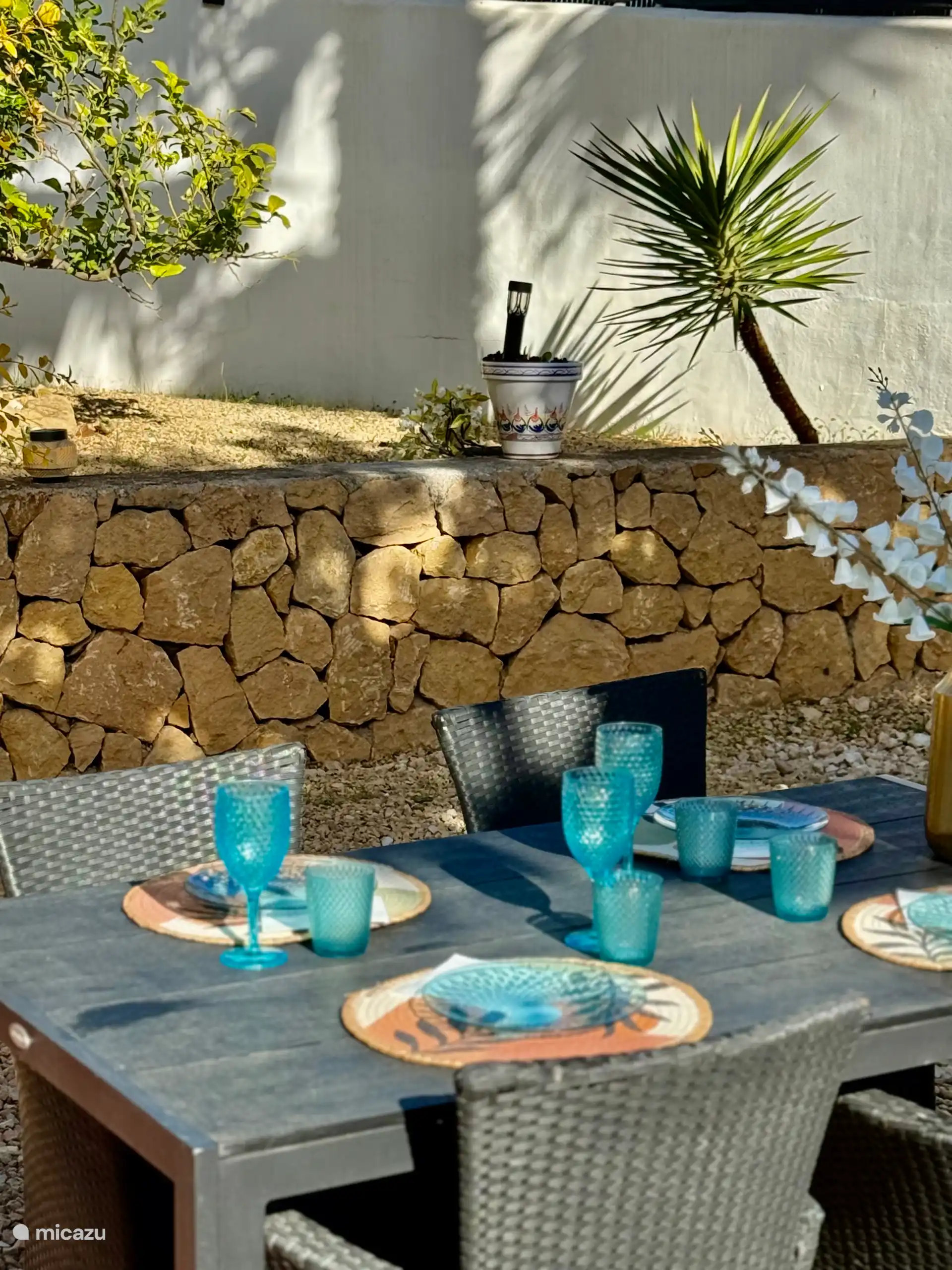Garden with large dining table with shade cloth and private sunbeds.