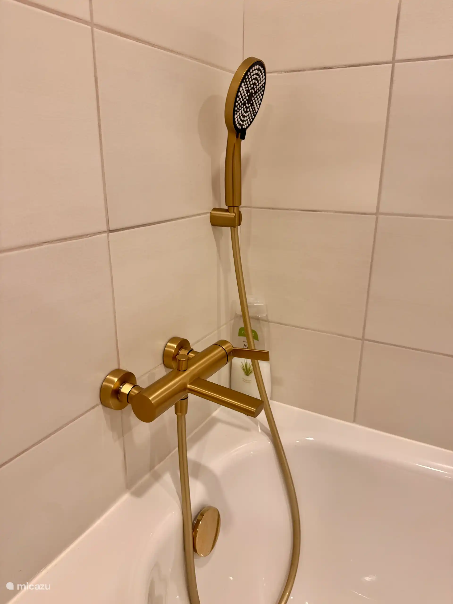 Large new bathtub with gold-colored tap.