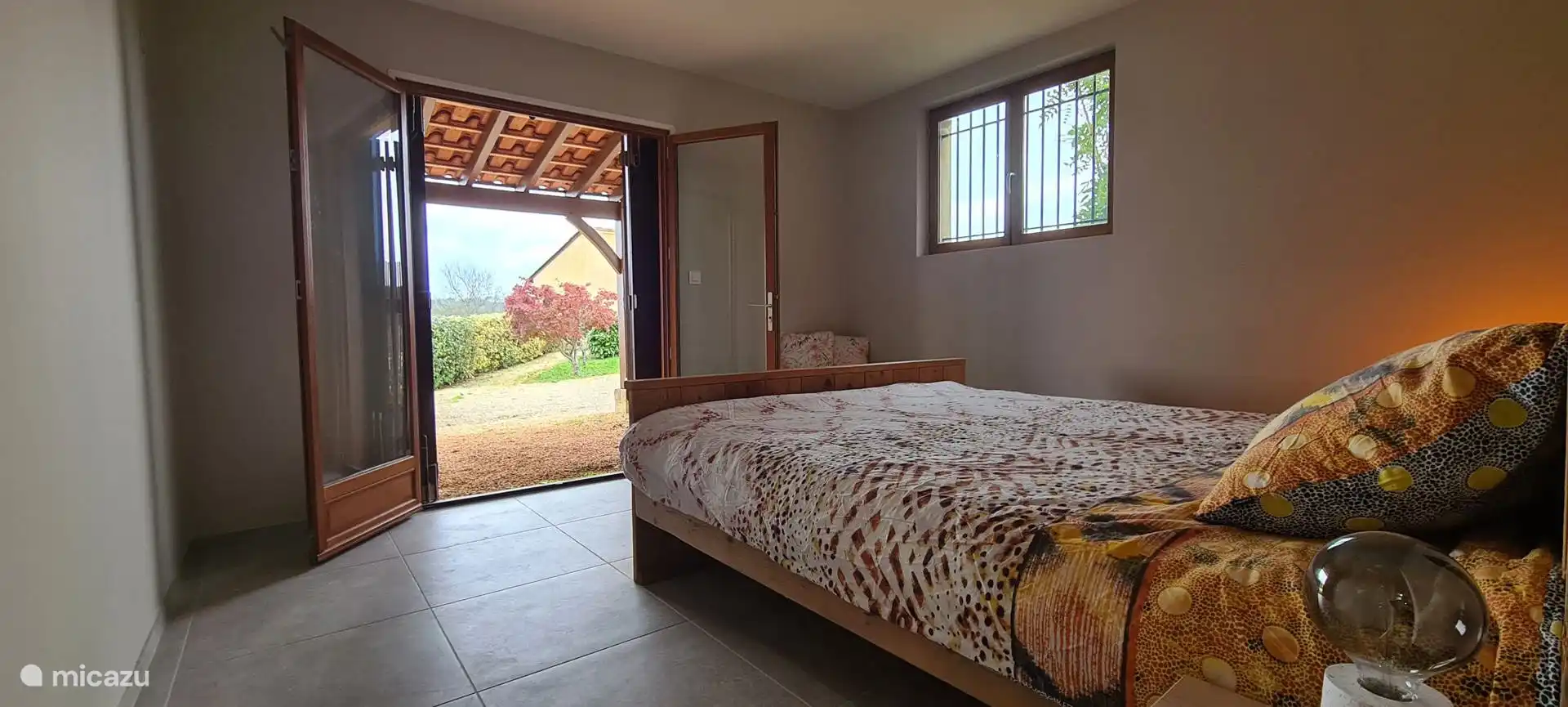 Downstairs bedroom with patio doors to the garden and double bed (180×200) with topper. Equipped with cushions, blanket, make-up table, full-length mirror and wardrobe.