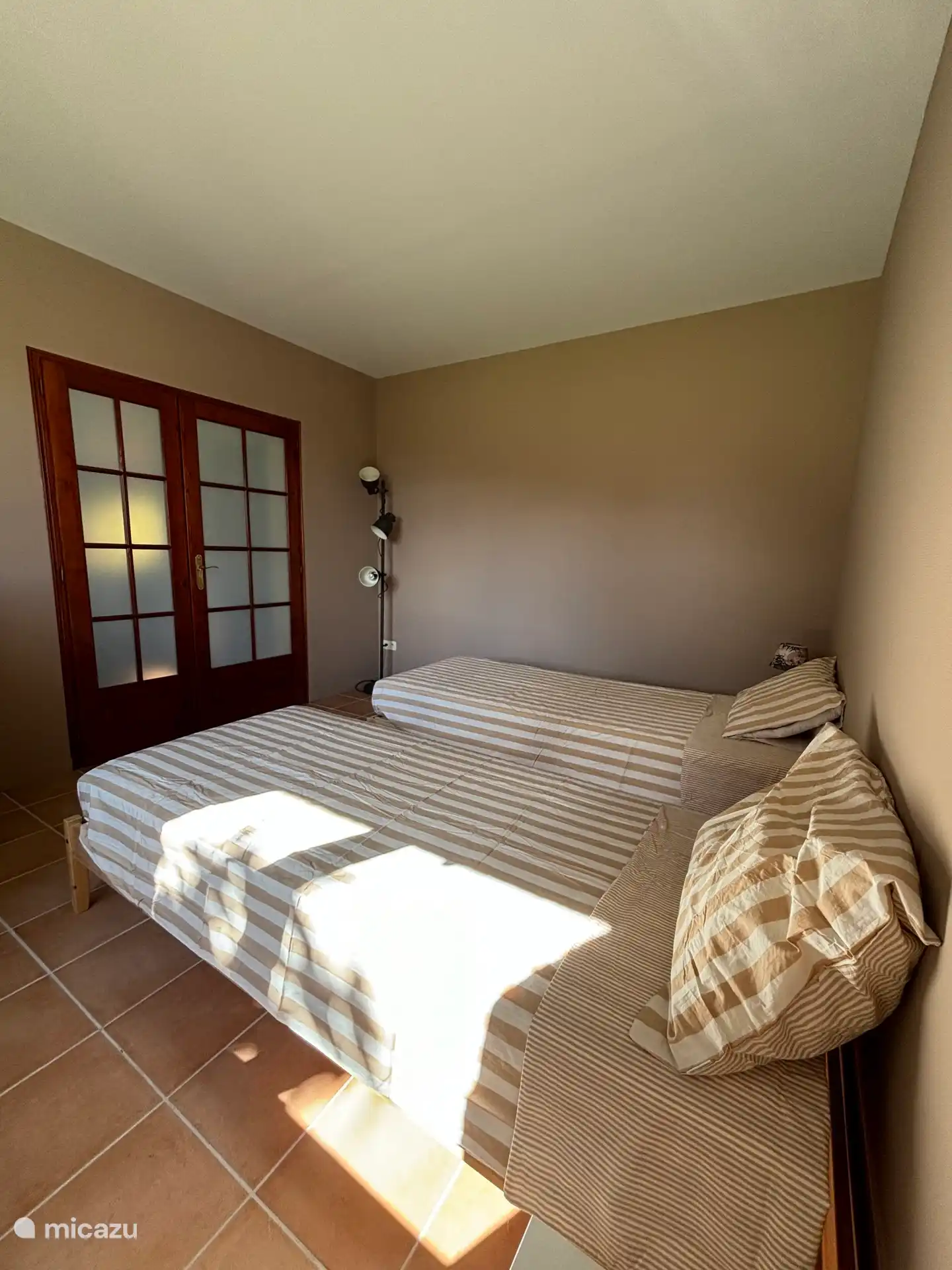 Bedroom with two single beds and a work area. Adjacent to the living area near the kitchen. Bathroom is at the end of the hallway. Equipped with blankets, pillows, bedside tables and wardrobe.