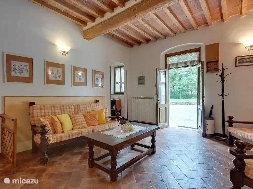Salon confortable avec poutres traditionnelles en bois, mobilier de style toscane et accès direct au jardin.