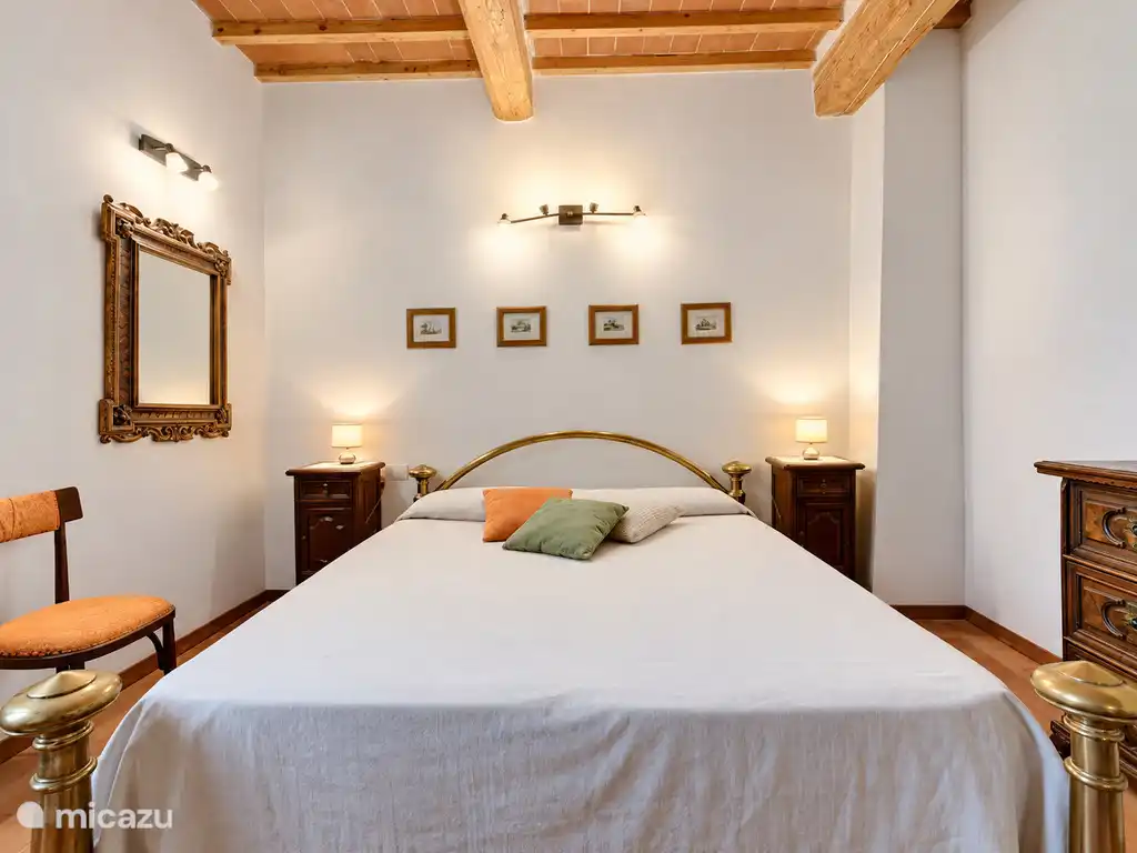 Double chambre avec meubles en bois, miroir décoratif et plafond en poutres apparentes.