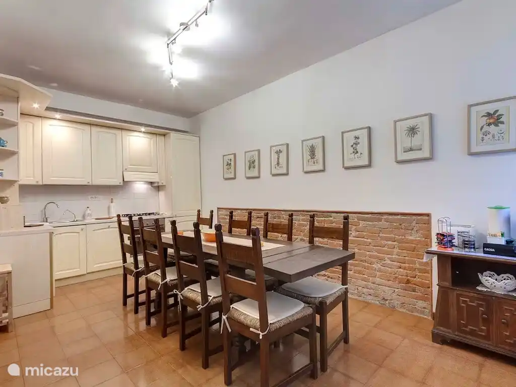 Cuisine entièrement équipée avec une grande table à manger en bois et des détails en briques apparentes.