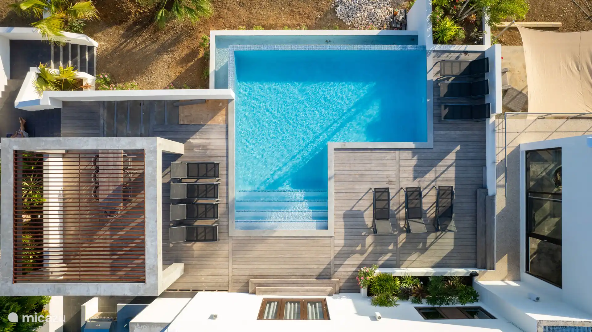 Piscina privada propia con camas de playa.