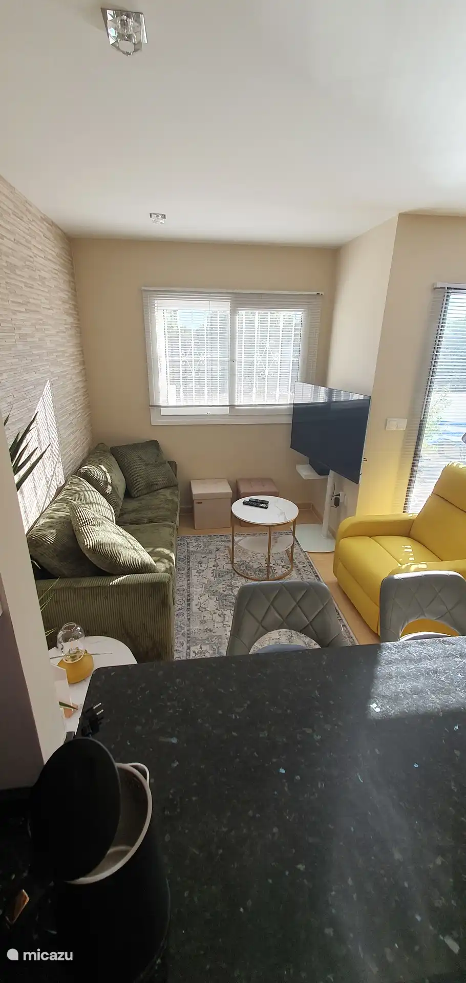 De gezellige woonkamer is ingericht in Ibiza-stijl met een comfortabele zetel, fauteuil en salontafel. Ontspan voor de smart-tv na een dag aan het zwembad of op de golfbaan. 
