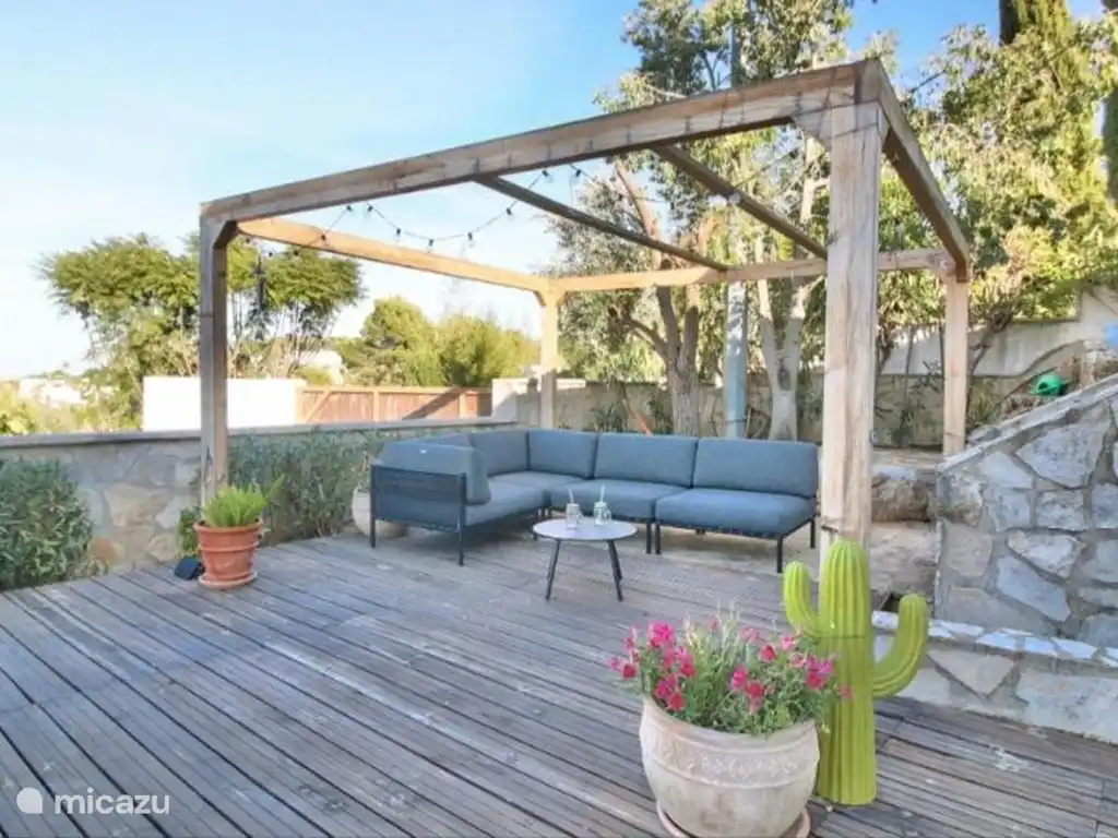 Loungehoek onder de pergola met lichtsnoeren, gezellig nagenieten op zomeravonden