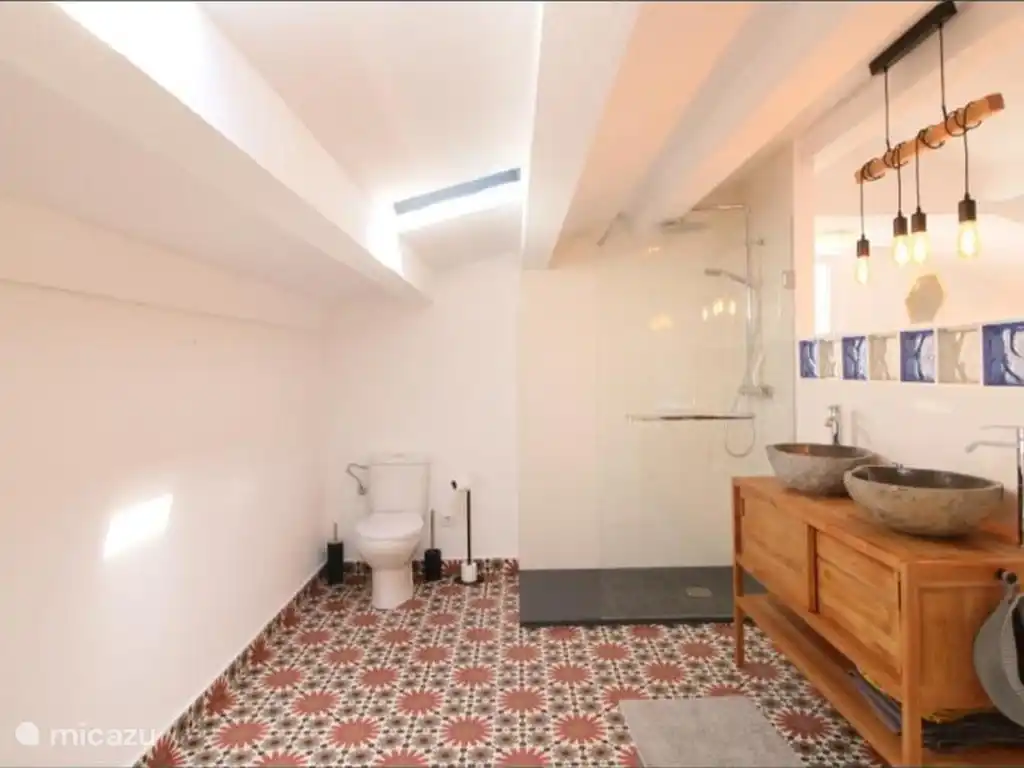 Sfeervolle badkamer op zolder met regendouche en stenen waskommen, een stukje luxe