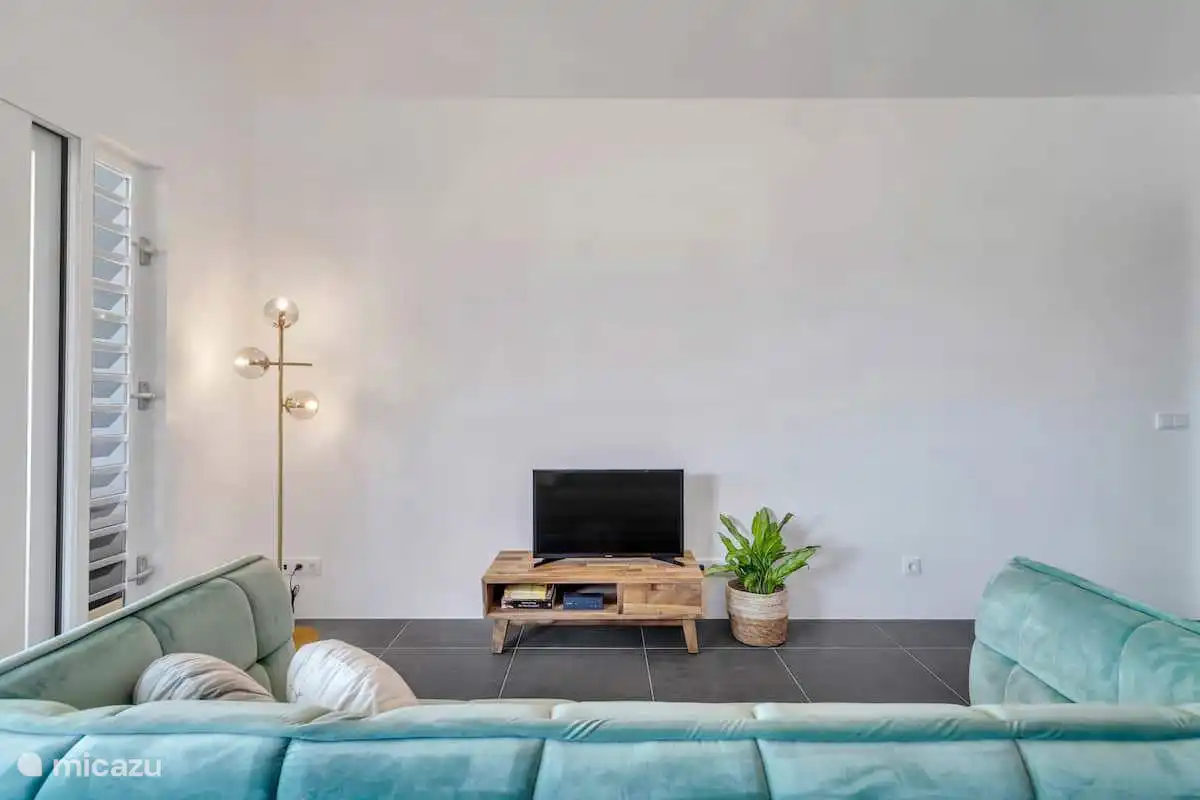 Helles Wohnzimmer mit Fernseher und Sitzecke.