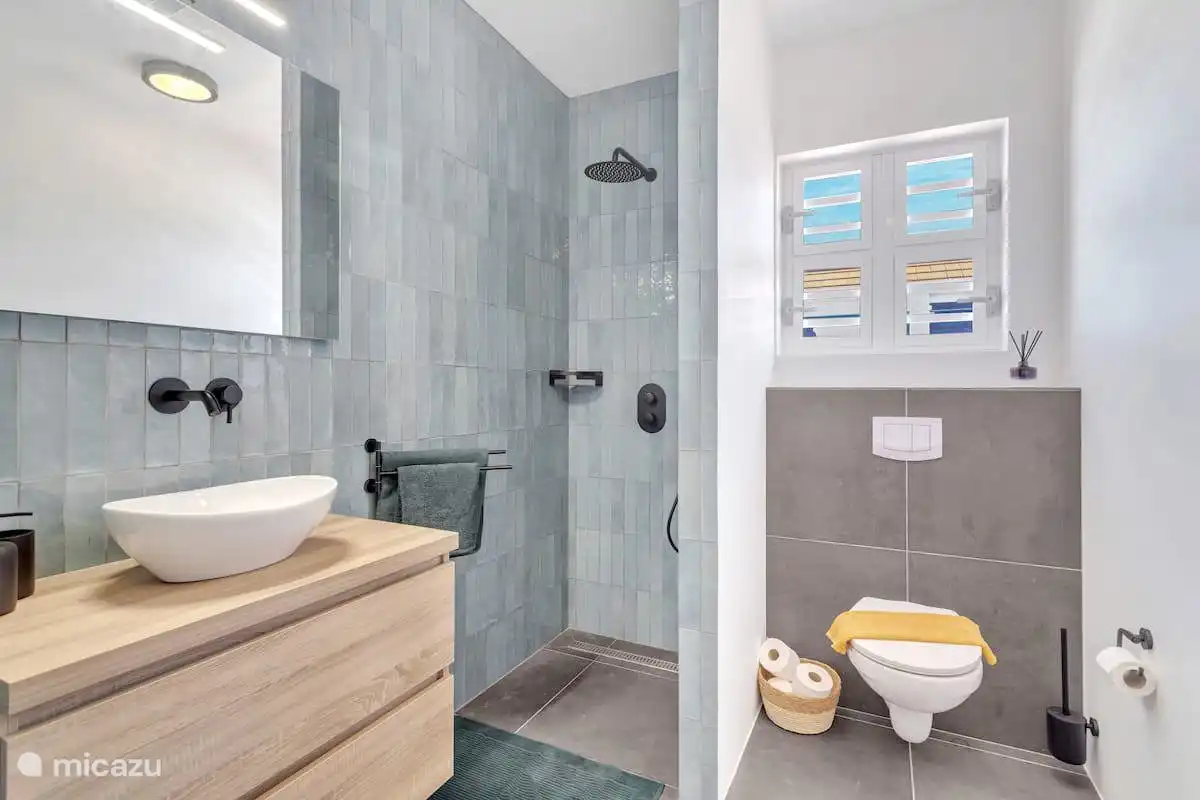 Badezimmer mit Dusche, Waschbecken und Toilette.