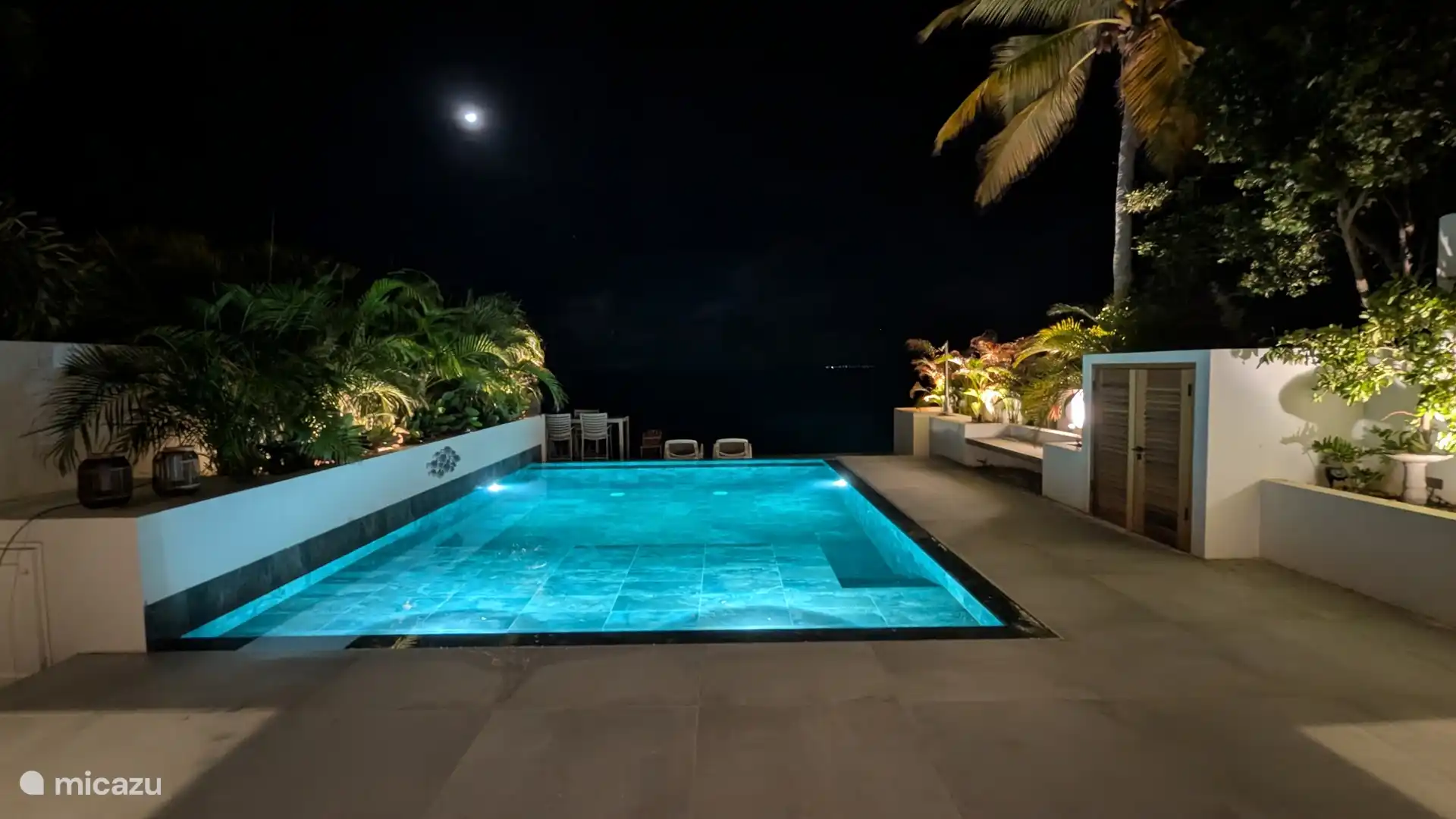 The private swimming pool is illuminated in the evening.