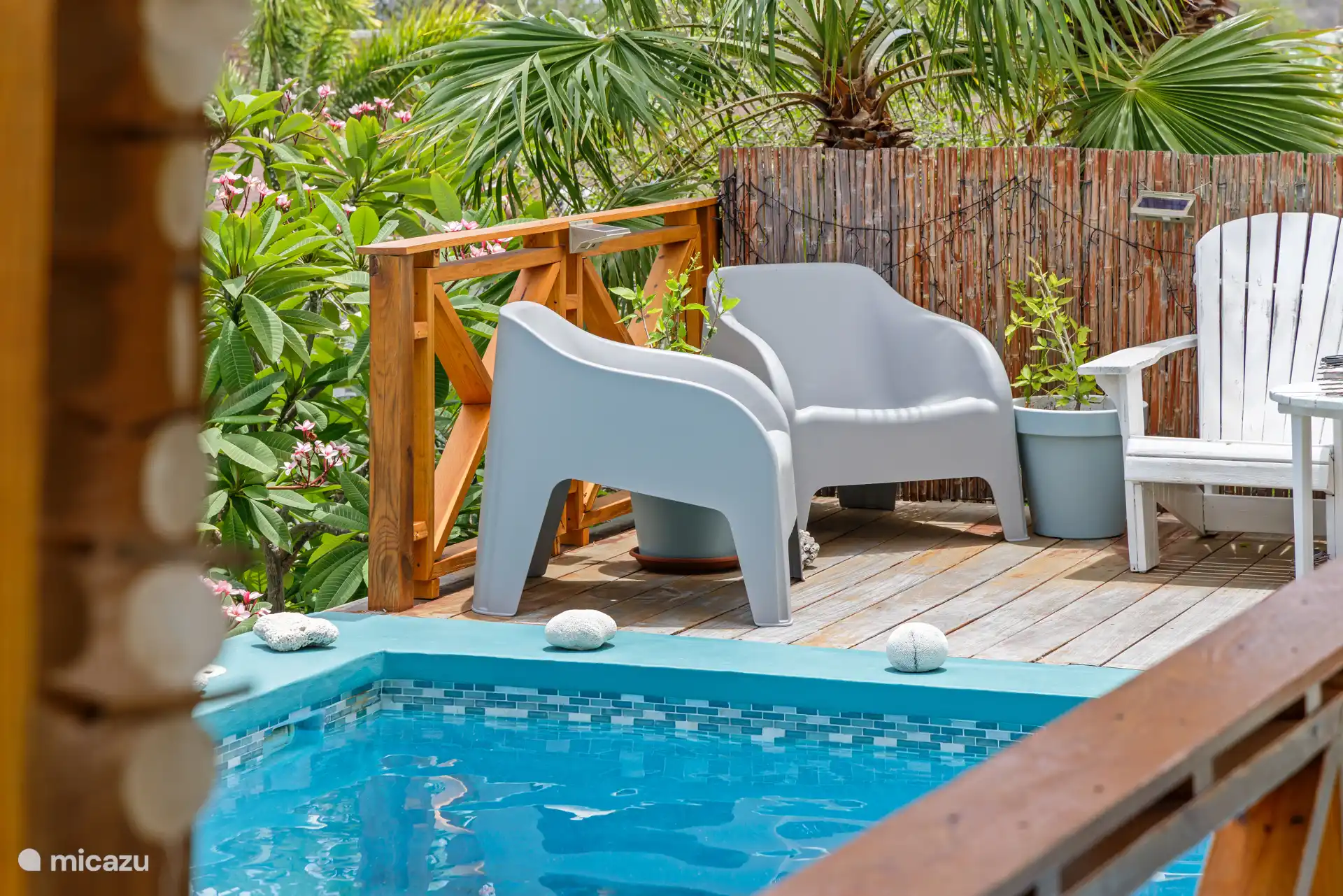 Geniet van een rustig moment in de comfortabele stoelen, omringd door tropisch groen en vlak bij het zwembad. Zie jij jezelf hier al ontspannen tijdens je vakantie?