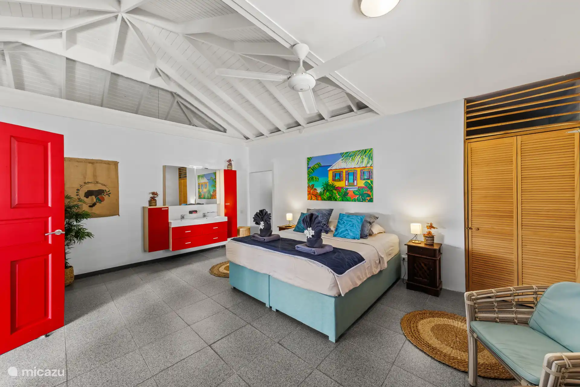 Een ruime, sfeervolle slaapkamer met een comfortabel tweepersoonsbed, zachte kleuren en tropische accenten. De perfecte plek om na een dag vol zon en avontuur heerlijk tot rust te komen.